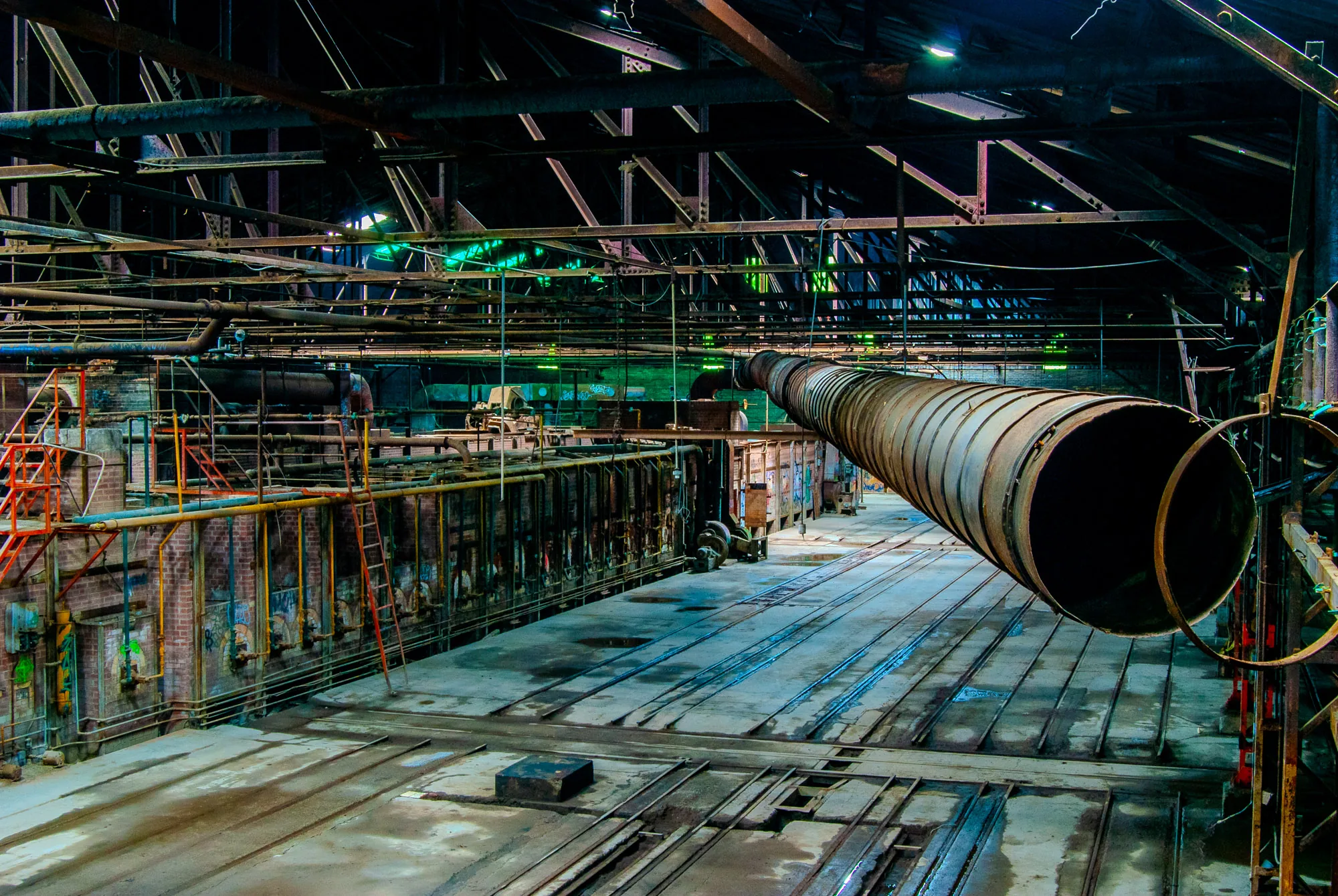 Large pipe running through an abandoned industrial factory interior, urban exploration photography