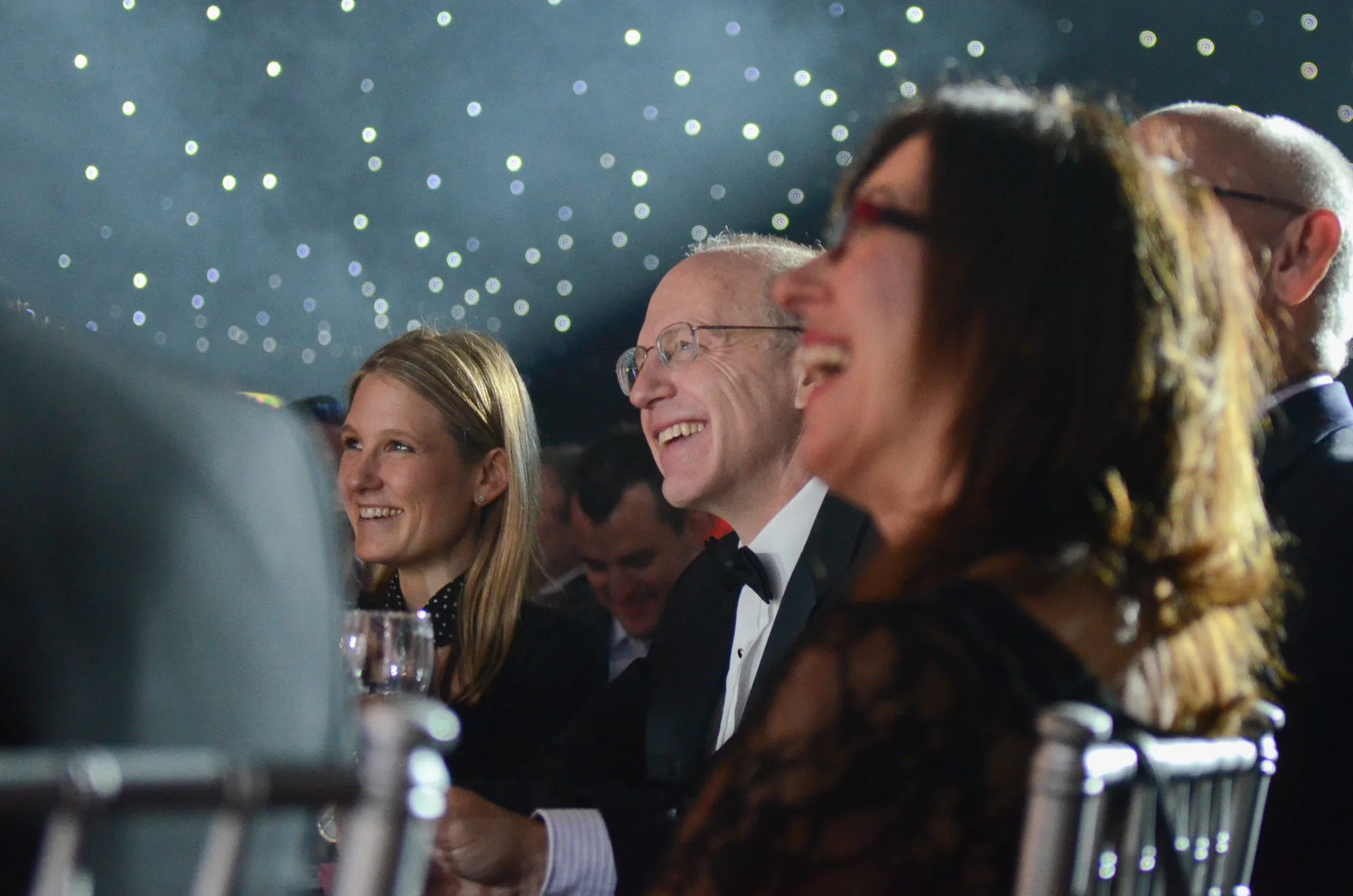 Guests smiling at a black-tie awards dinner table, corporate event photography by Hector's Eye