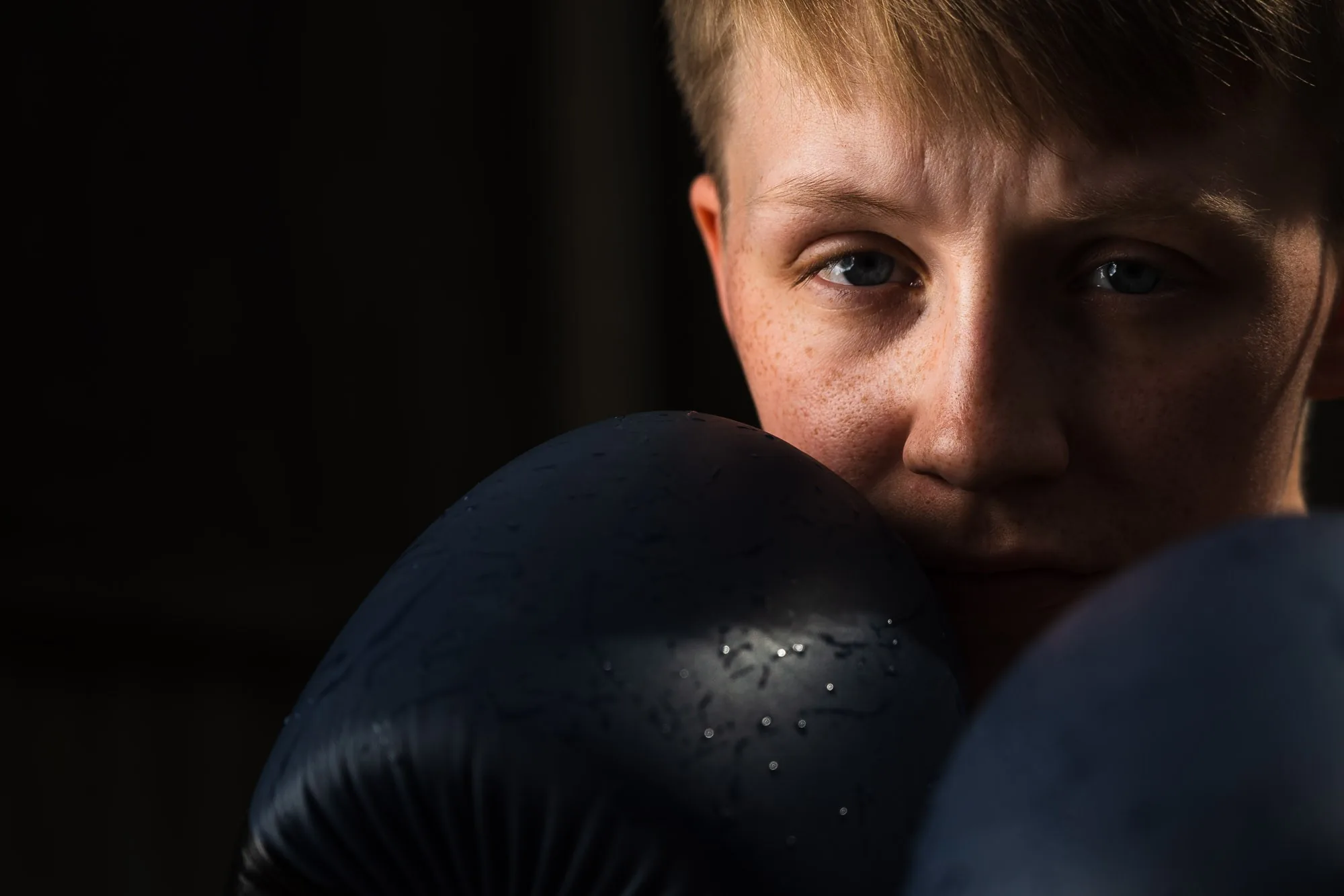 Close-up portrait of a young boxer with a raised glove, editorial portrait photography by Hector's Eye