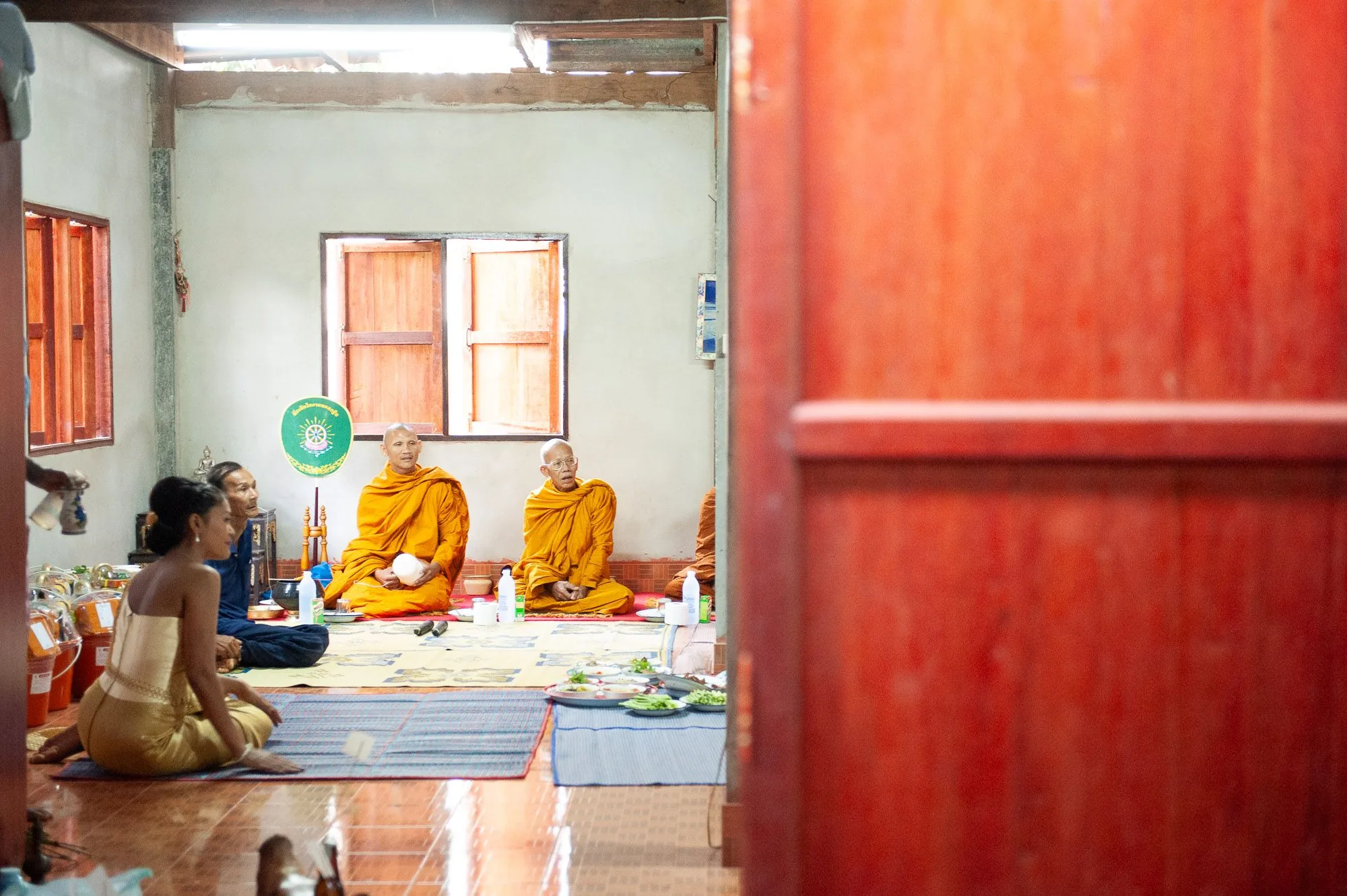 Buddhist monks blessing a couple during a wedding ceremony on a temple floor, wedding photography by Hector's Eye