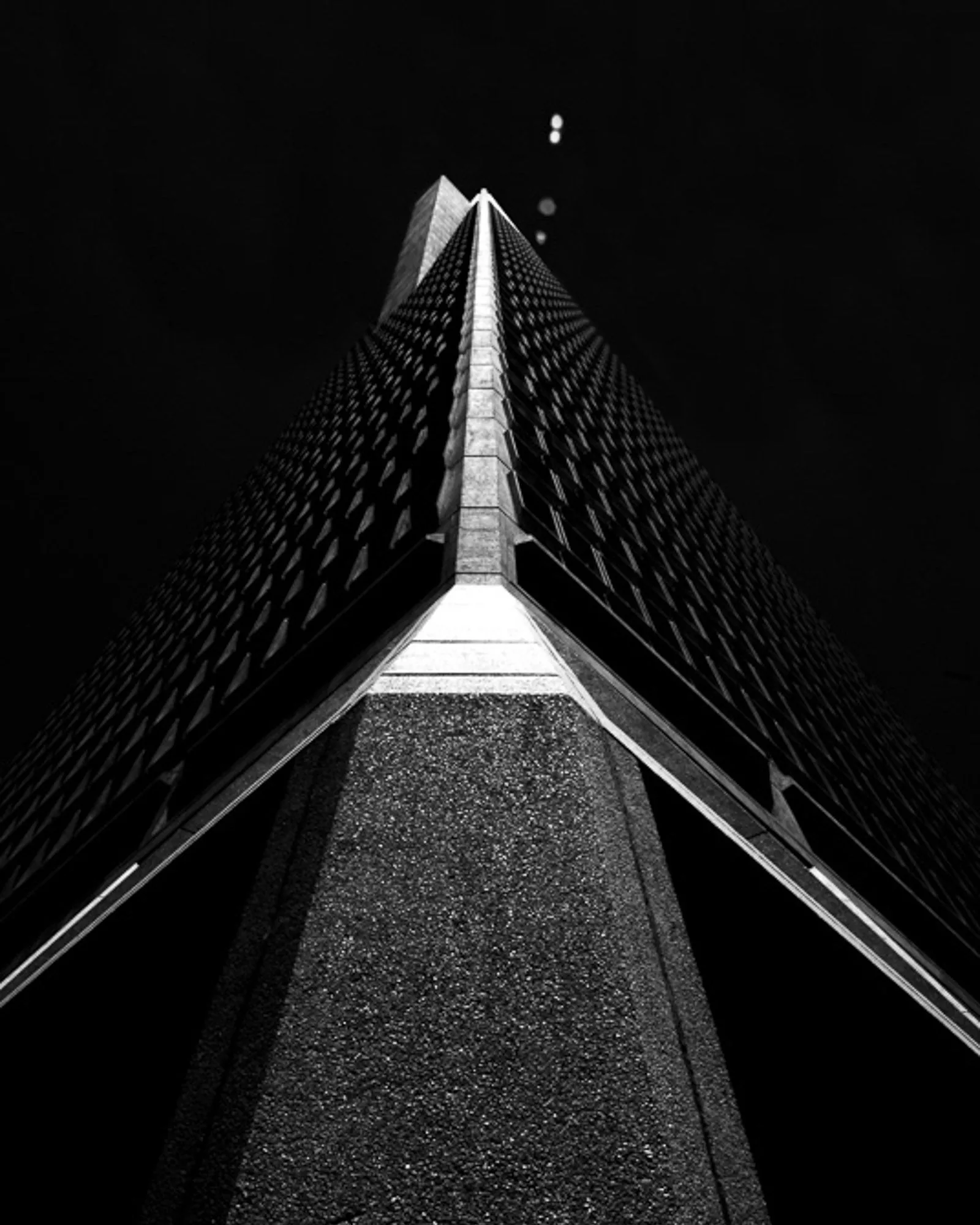 Black and white view looking up the tower of a cable-stayed bridge at night, architectural photography by Hector's Eye