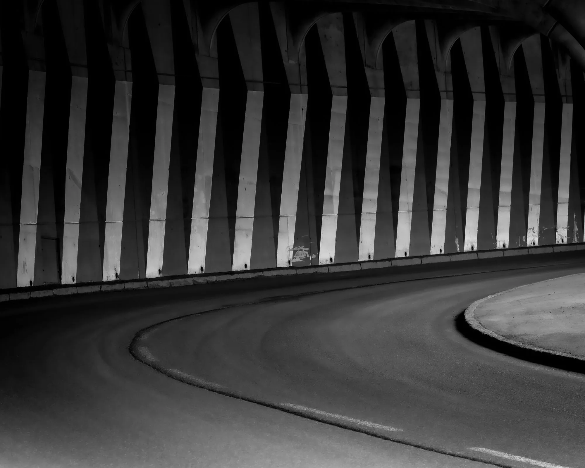 Repeating concrete arches inside a road tunnel at night