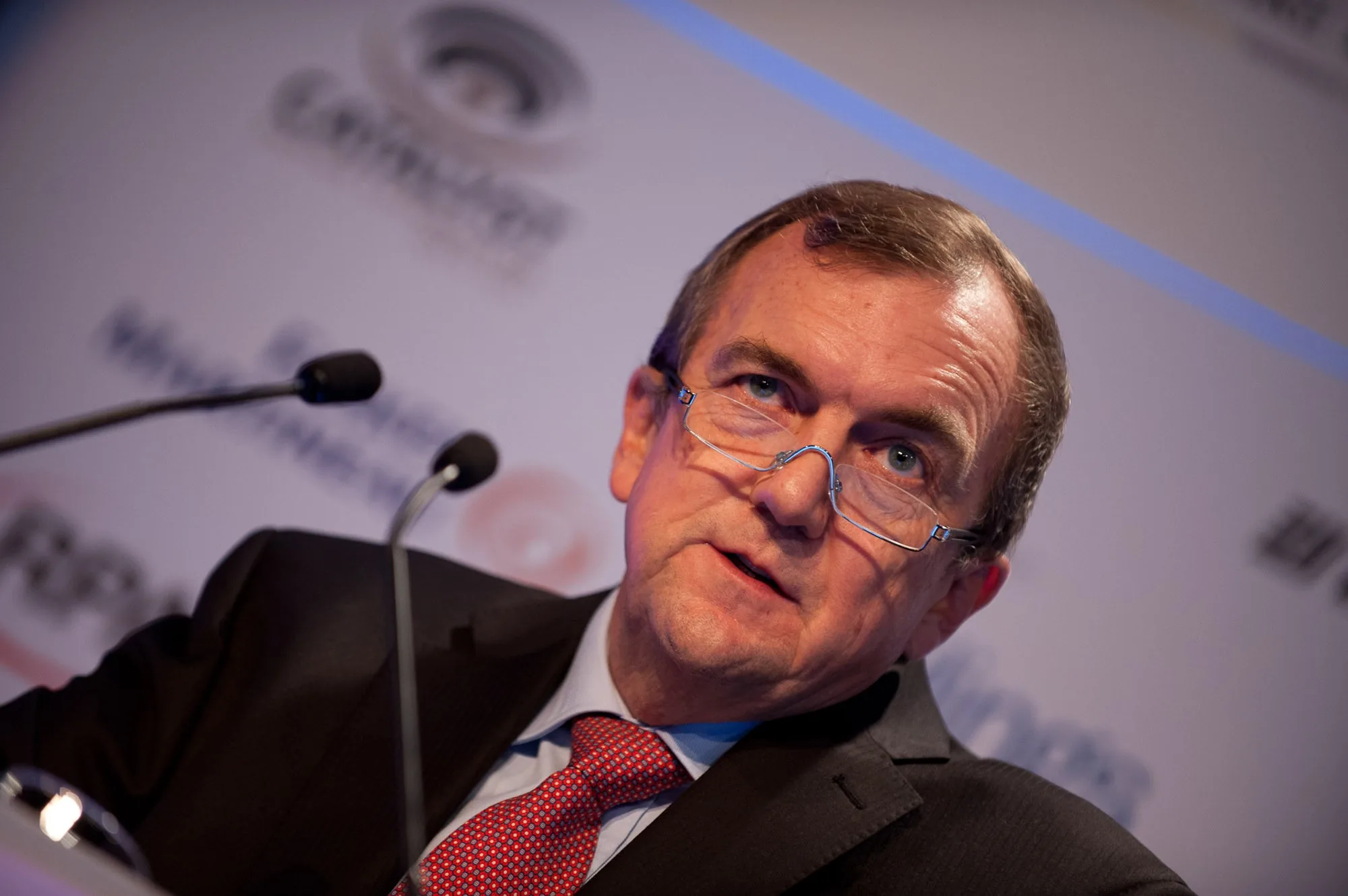 Speaker addressing an audience from a lectern at a corporate conference, event photography by Hector's Eye