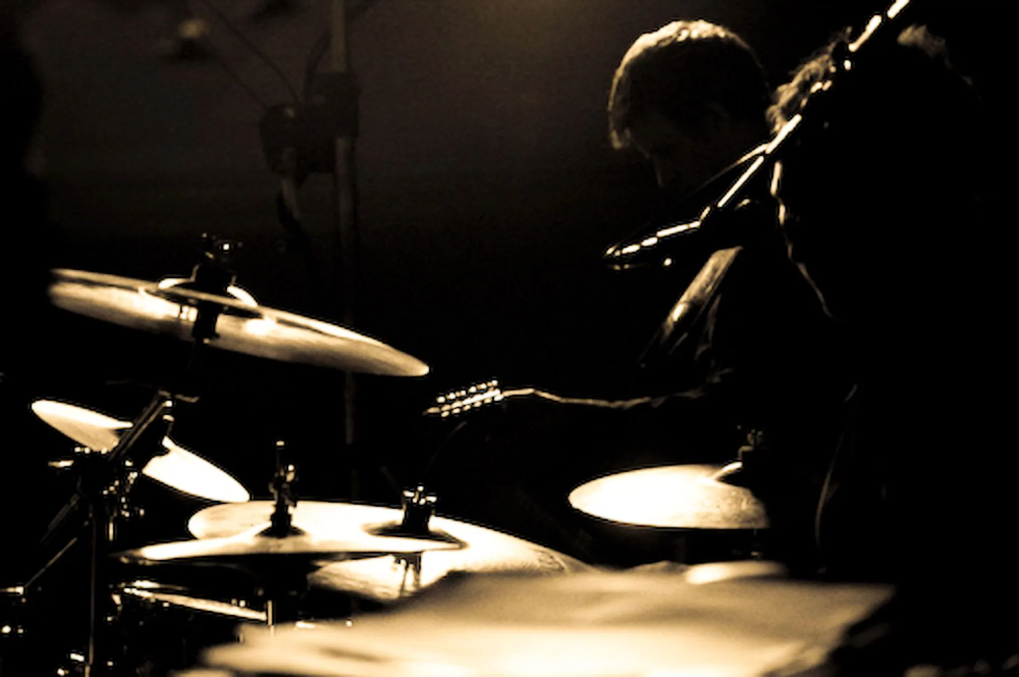 Drummer silhouetted against warm stage lighting, live music photography by Hector's Eye