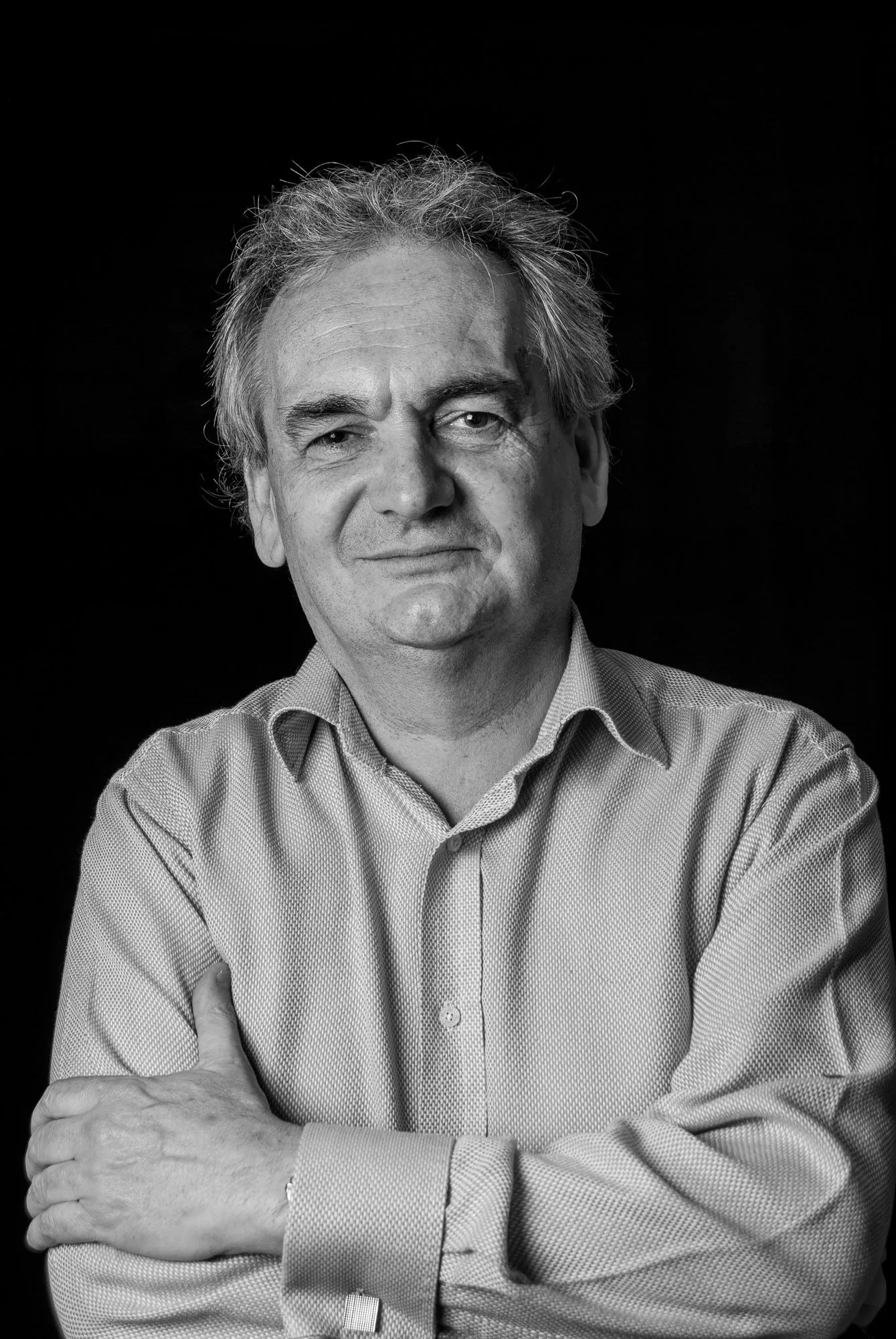 Black and white studio portrait of a man with arms folded, editorial portrait photography by Hector's Eye