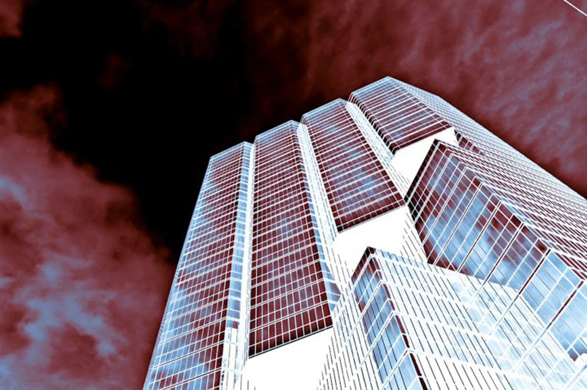 Looking up at a glass skyscraper against a dramatic red infrared sky, abstract photography