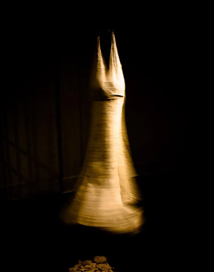 Hanging textile sculpture lit dramatically against a dark background, art documentation photography by Hector's Eye for Kat Hayes