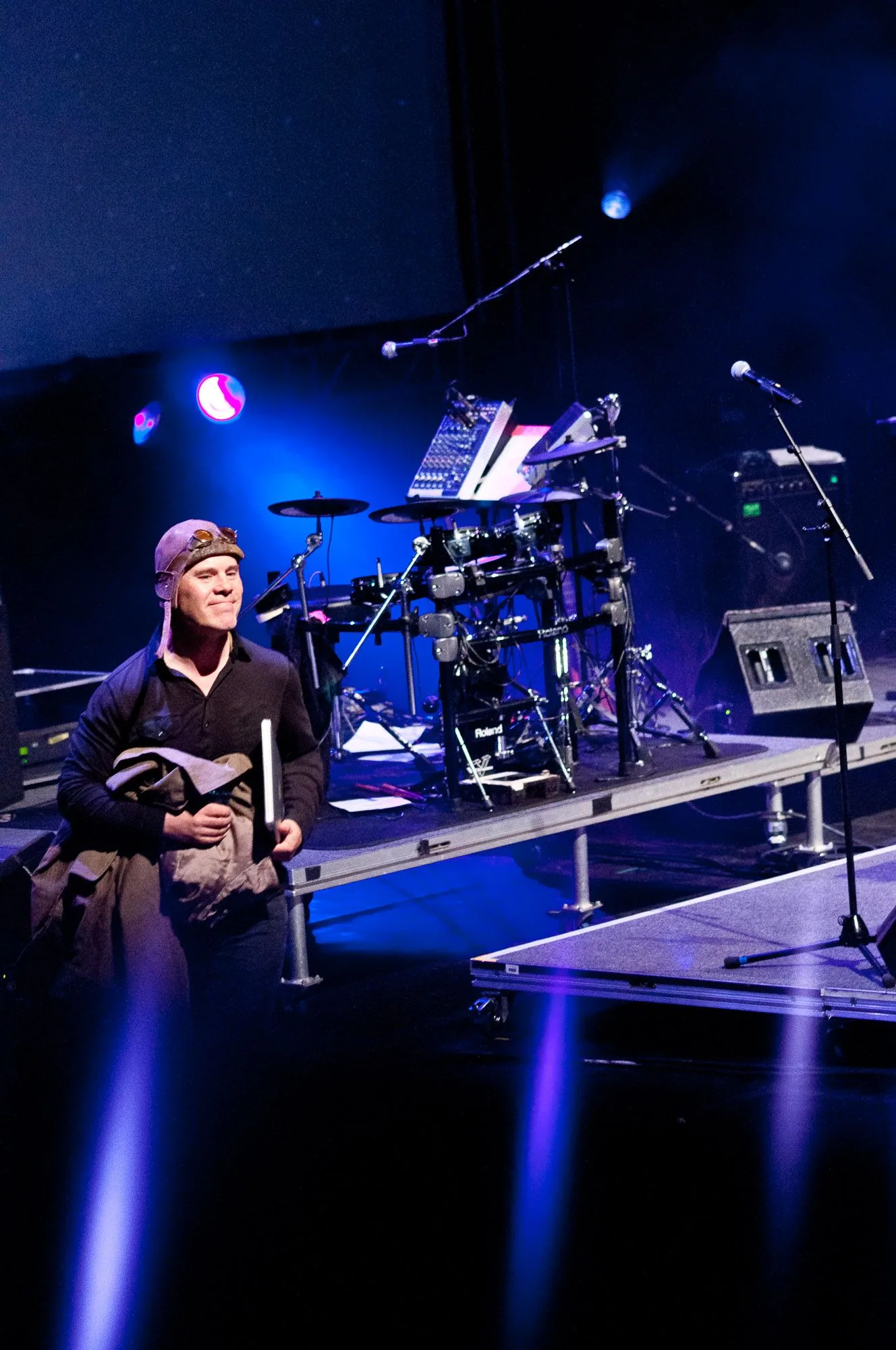 Musician relaxing backstage in front of an electronic drum rig, live music photography by Hector's Eye