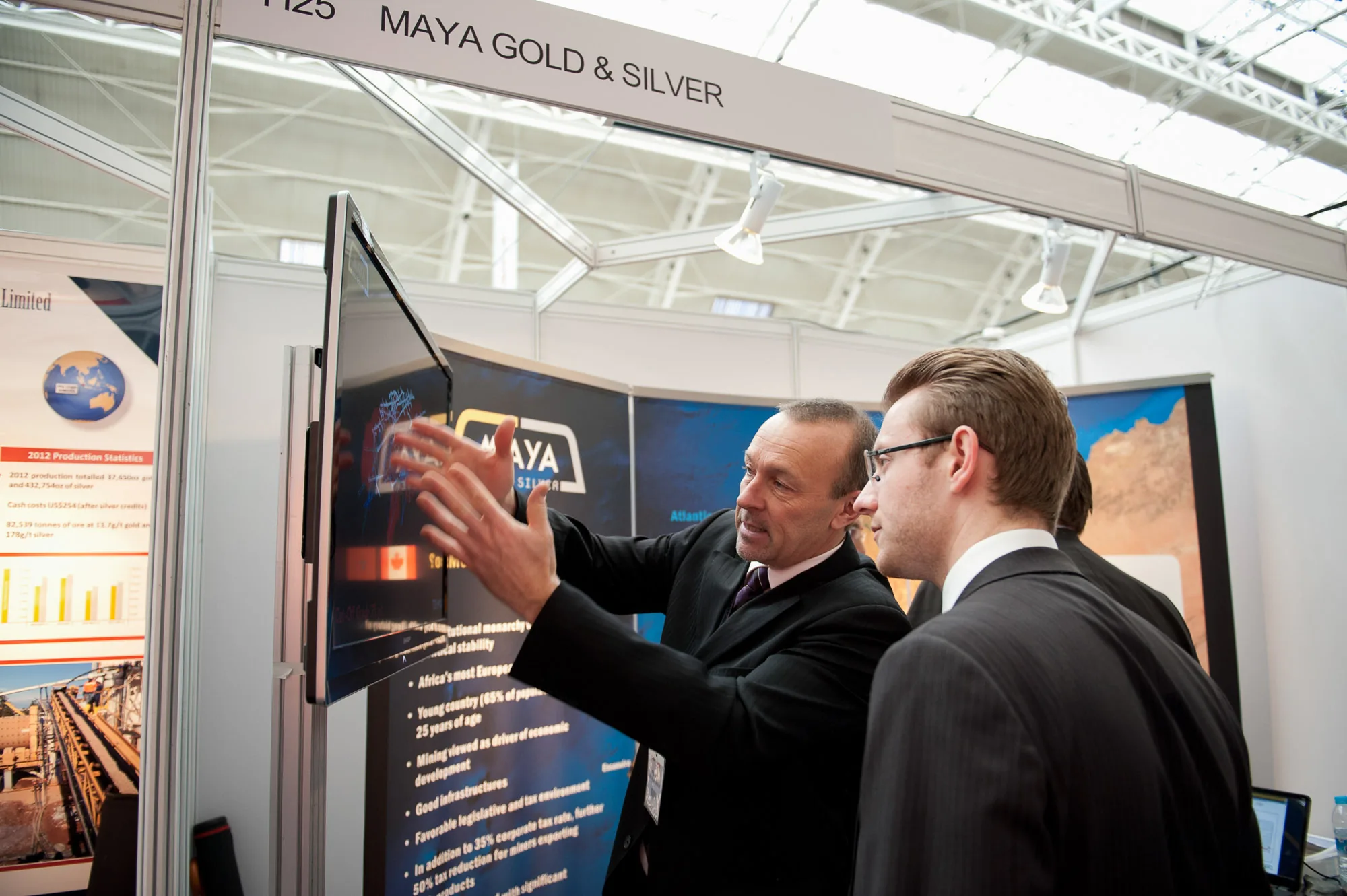 Delegates viewing a presentation screen at a mining conference exhibition stand, corporate event photography by Hector's Eye