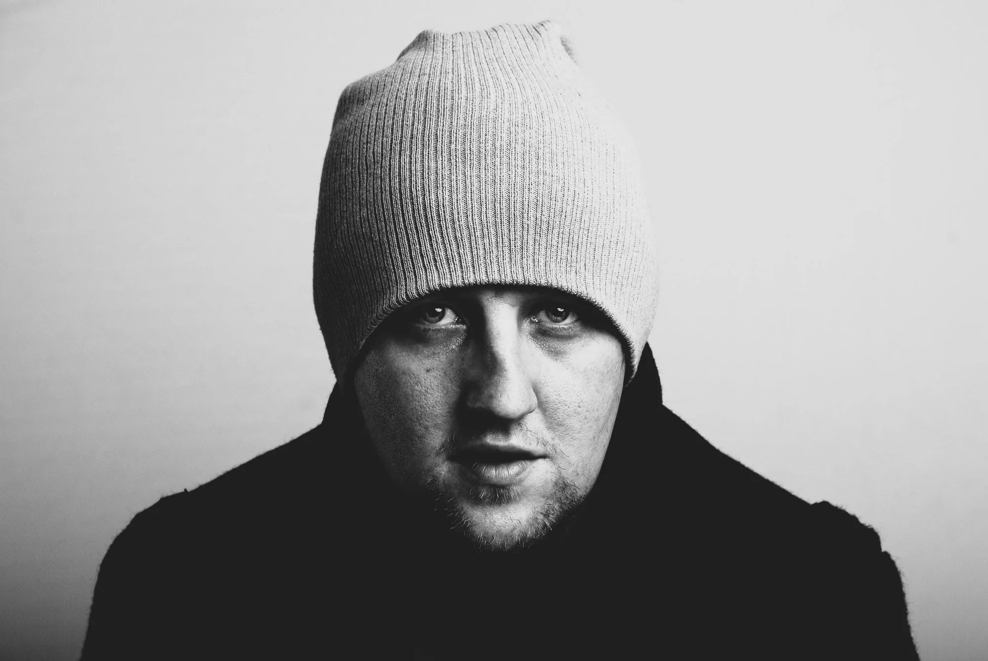Moody black and white close-up portrait of a man wearing a beanie hat, editorial portrait photography by Hector's Eye