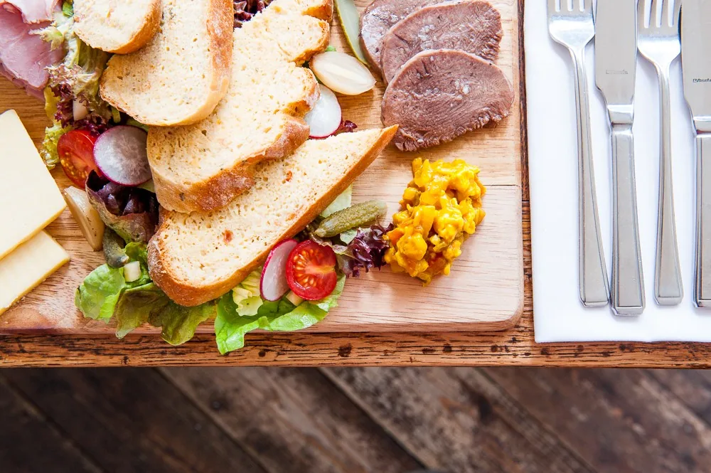 Overhead shot of a ploughman's sharing board with bread, cheese and cold meats, food brand photography by Hector's Eye