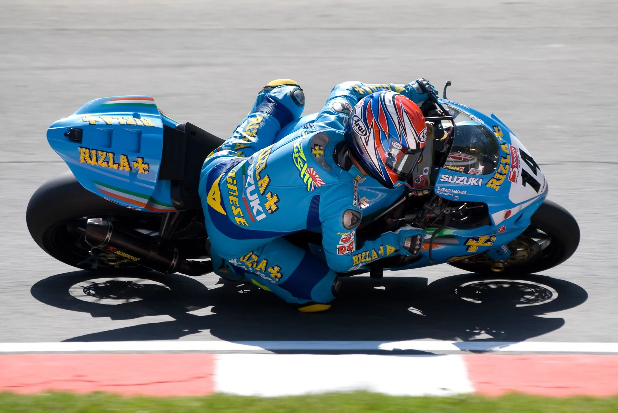 Liveried racing motorcycle leaning into a corner on a race track, motorsport photography by Hector's Eye