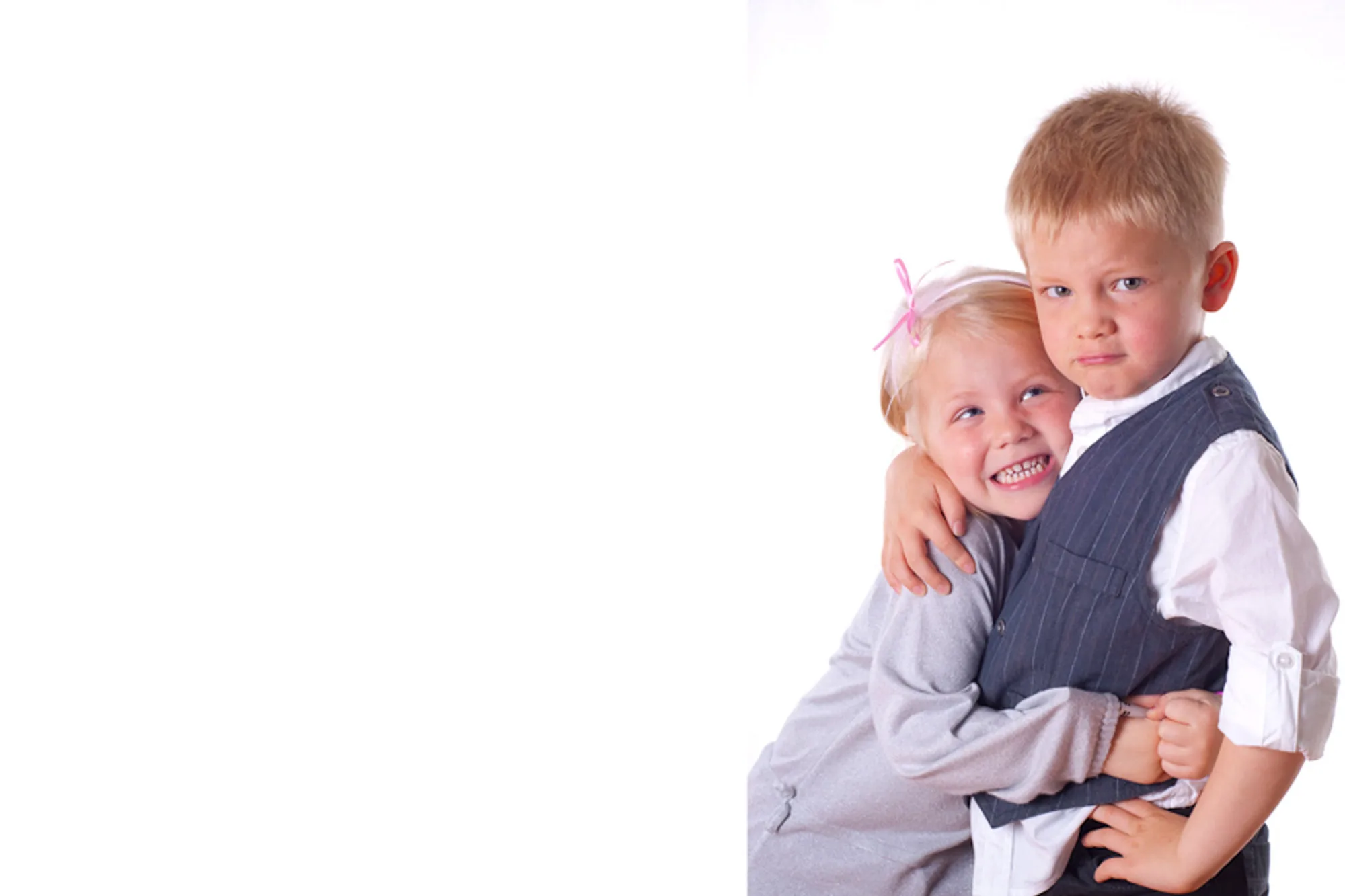Two young siblings hugging and smiling in a studio portrait by Hector's Eye