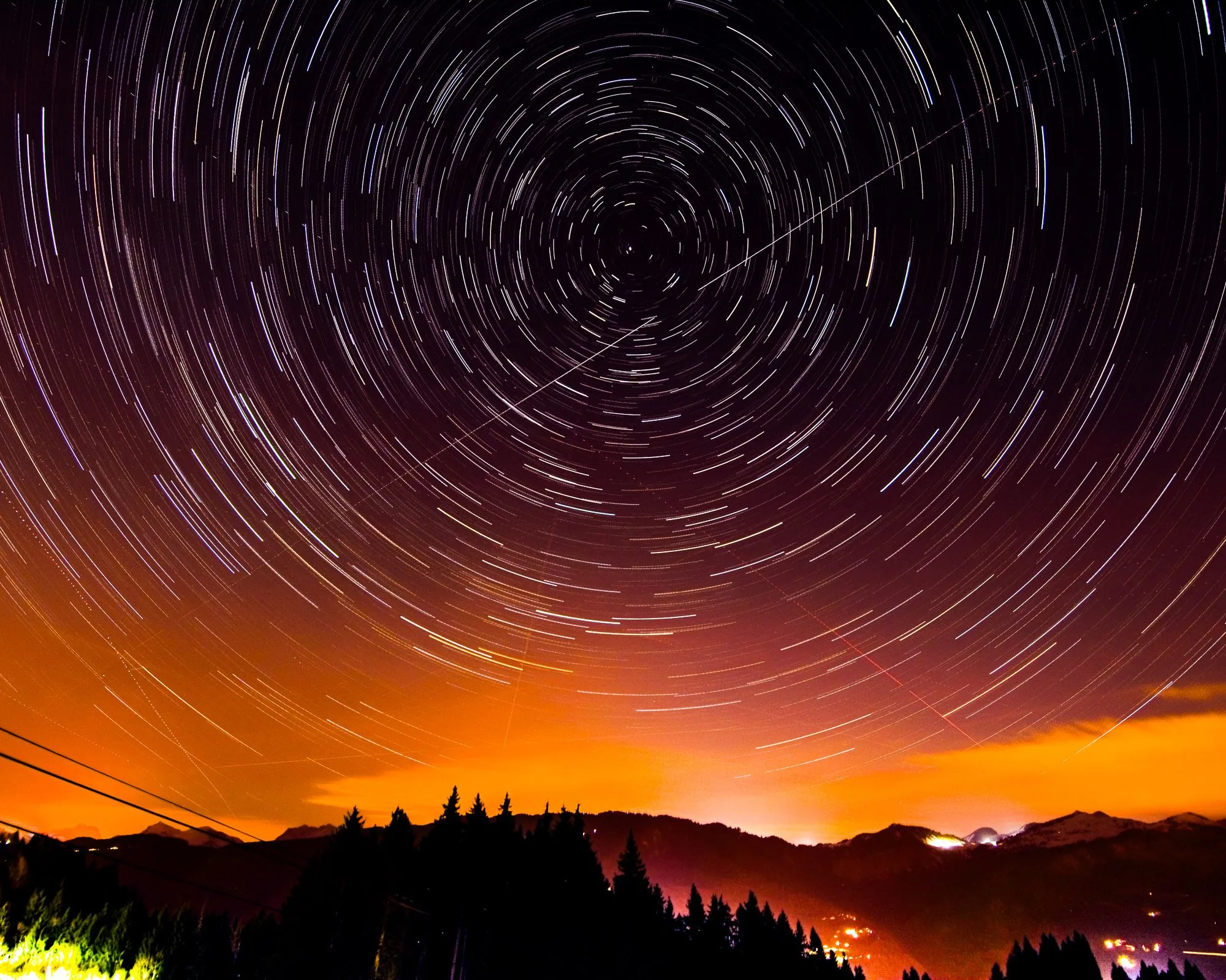 Star trails circling over a mountain landscape at dusk, night sky landscape photography by Hector's Eye