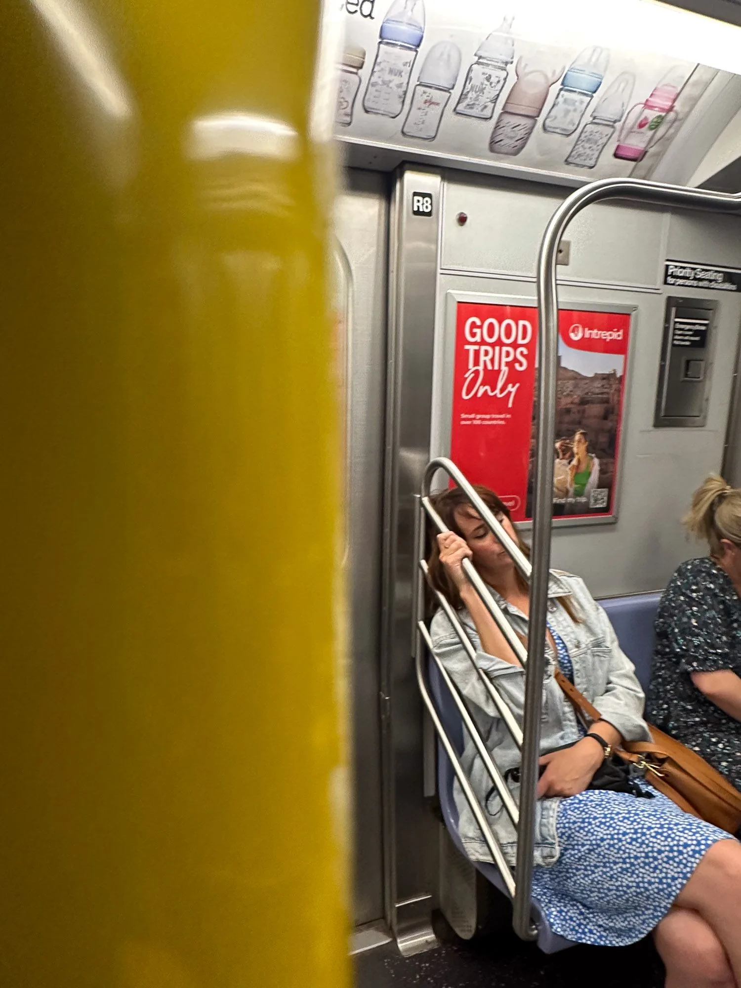 Candid shot of a woman resting against a pole on a subway train