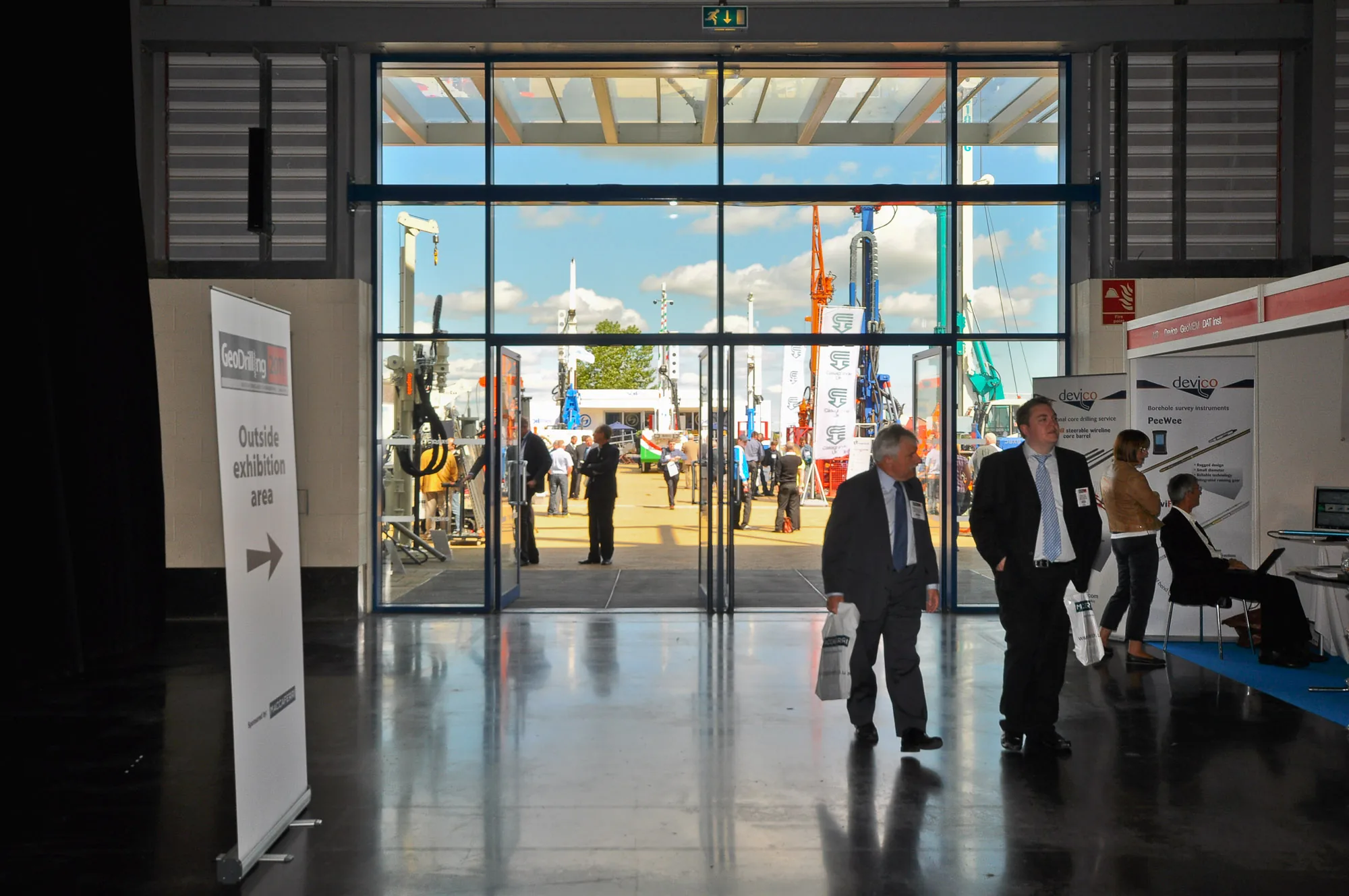 Delegates walking through a bright exhibition hall entrance at a trade show, corporate event photography by Hector's Eye