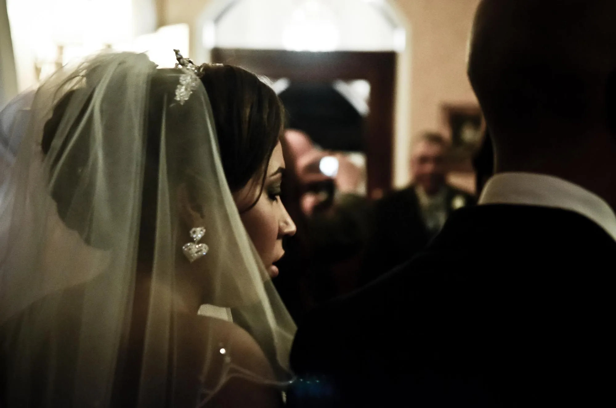 Bride in profile wearing a veil during a wedding ceremony, candid reportage wedding photography by Hector's Eye